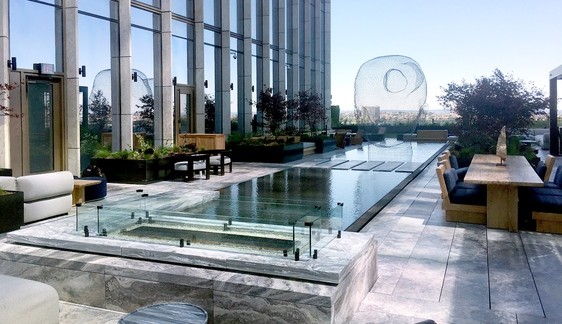 Beautiful still water reflecting pool with large transparent sculpture. Water constantly overflows and laminates to the sidewalls of the water feature creating a shimmering block of water.